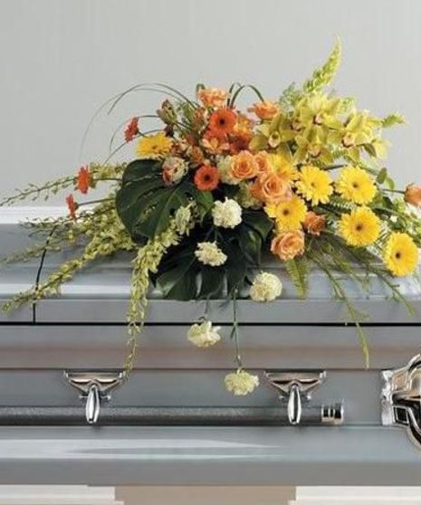 Casket spray of yellow, orange and green flowers including cymbidium orchids and roses. 