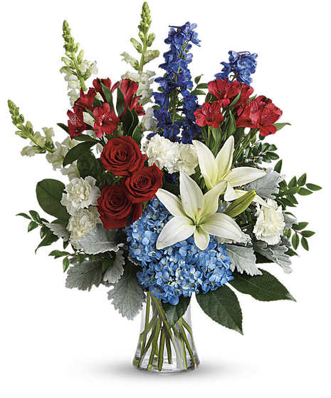 Glass rectangular vase filled with sand and seashells and designed with hydrangea, lilies, carnations and blue stars.
