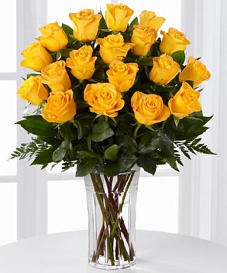 One dozen yellow roses in a clear glass vase with baby's breath.