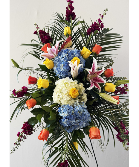 Sympathy spray with red carnations and roses presented on an easel. 