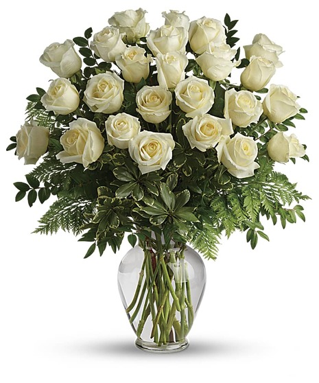 One dozen white roses and greenery in a clear glass vase.