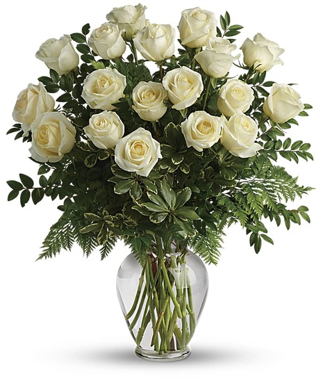 One dozen white roses and greenery in a clear glass vase.