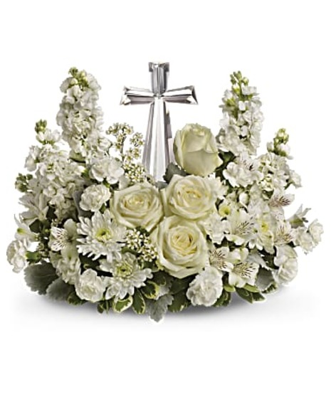 Crystal cross keepsake surrounded by white flowers. 