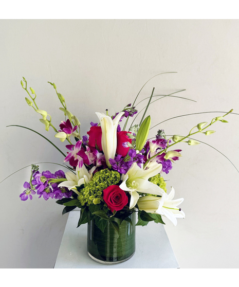 Cubed glass vase filled with orchids, roses, lilies and more.