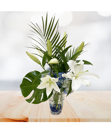 White hydrangea and pink lilies in a clear glass vase.